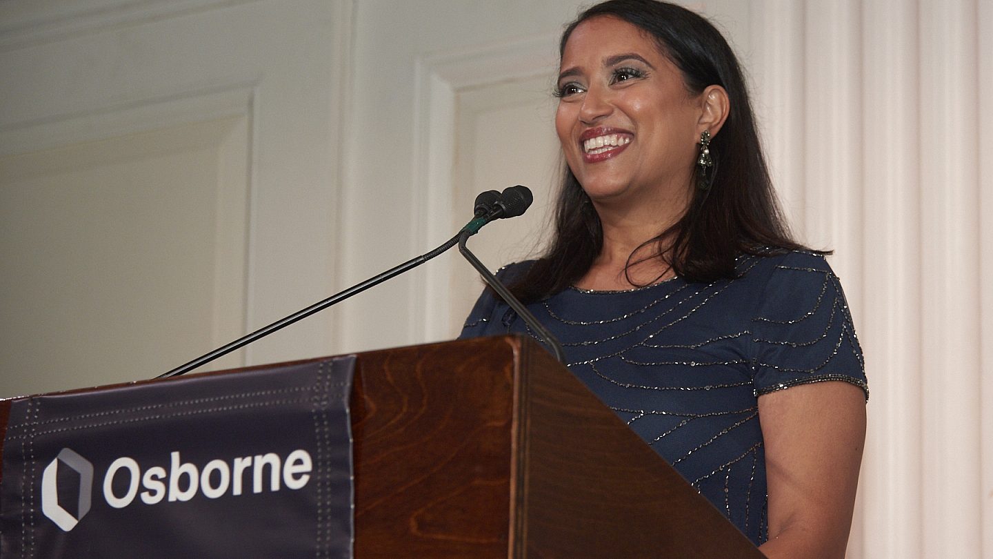 Osborne President and CEO Archana Jayaram smiling while standing at the podium.