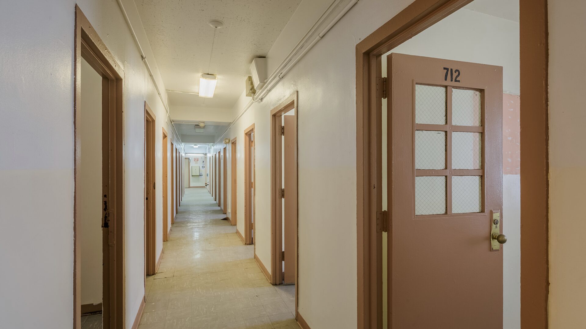 A hallway shot with 5 doors open on the right side and 5 on the left.